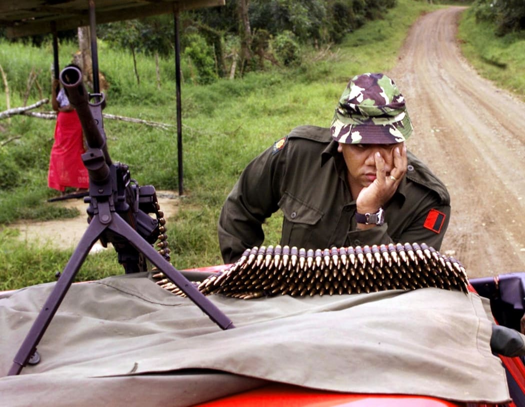 A soldier guards the road to Nasova village after a soldier and a policeman were killed in an ambush by the last rebel supporters of coup leader George Speight in Fiji 2000.