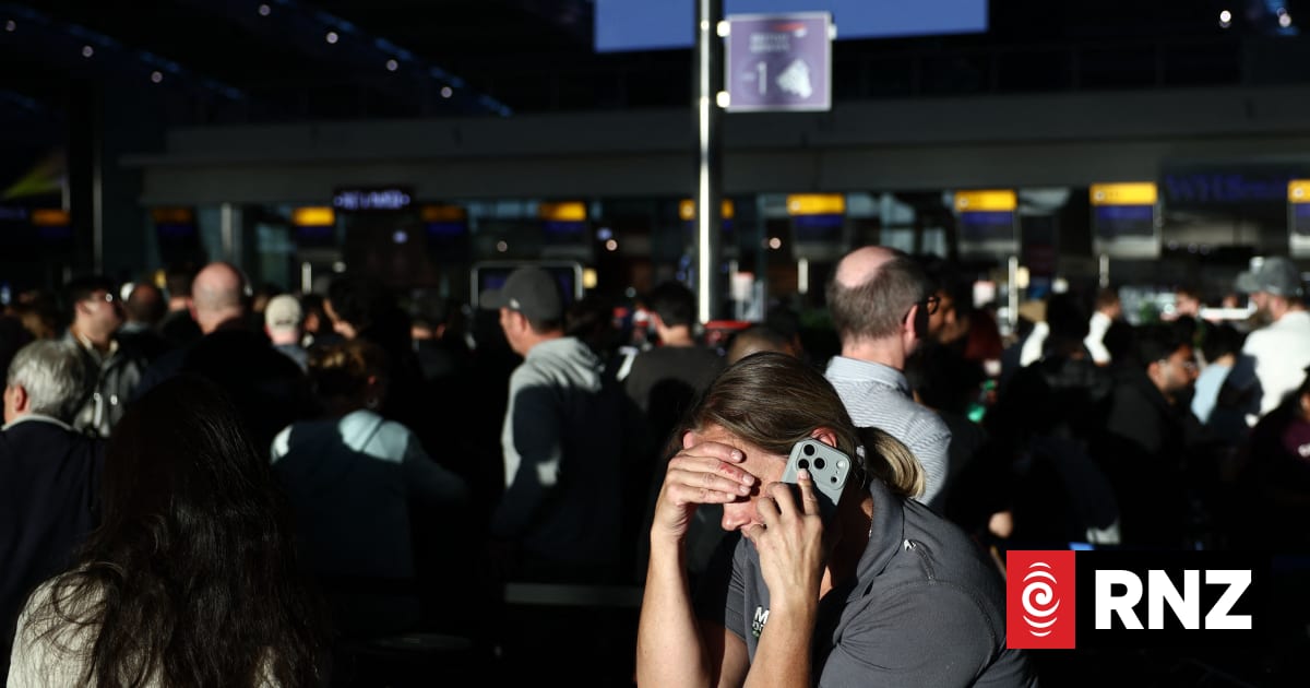 People stand with their luggage as the queue at check-in desks inside Terminal 5 of London Heathrow airport, west of London