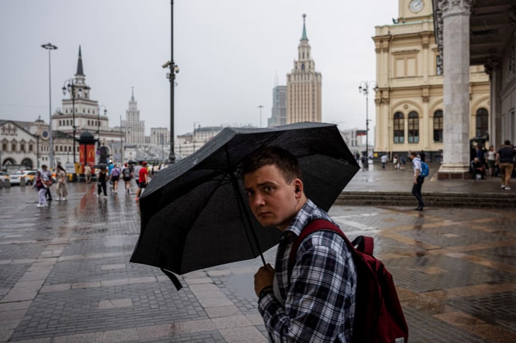 A man holds an umbrella during a rainy day at Three Station Square in Moscow on August 2, 2021. (Photo by Dimitar DILKOFF / AFP)
