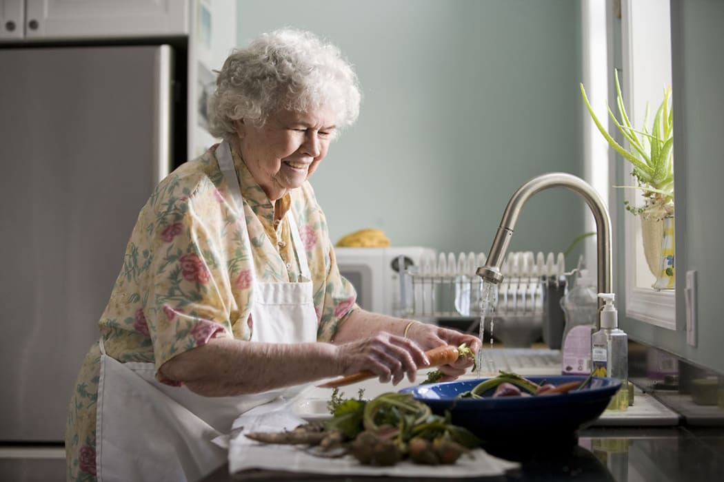 An elderly woman washing produce