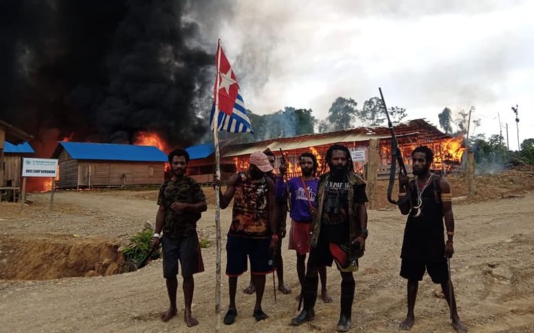 West Papua Liberation Army members outside the torched base camp of Indonesian logging company PT Bangun Katu Irian
