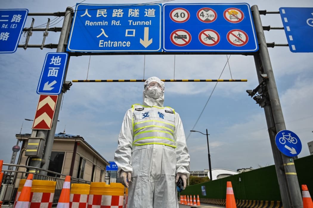 A transit officer, wearing a protective gear, controls access to a tunnel in the direction of Pudong district in lockdown as a measure against the Covid-19 coronavirus.