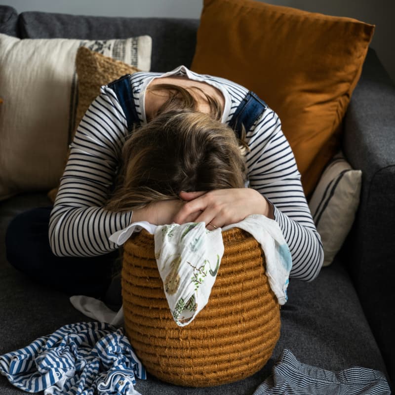 A woman slumps over a laundry basket.