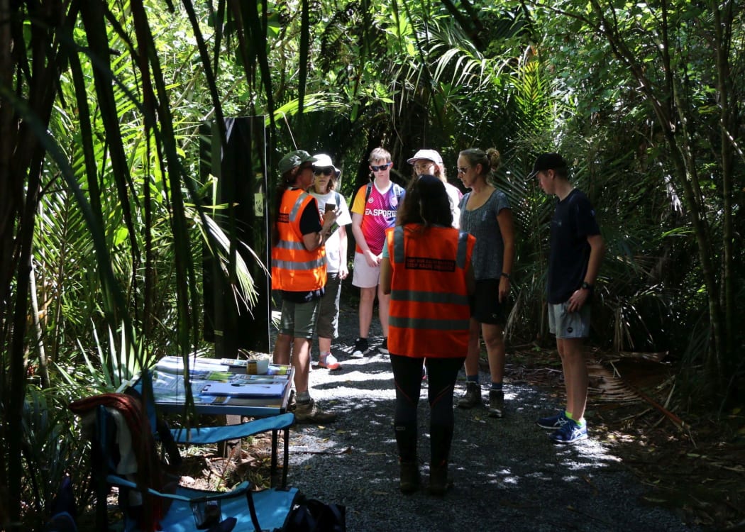 Auckland Council staff speak with walkers about Kauri dieback on Kitekite Falls trail.