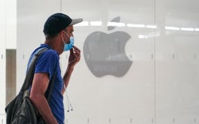 A man wearing a mask past an Apple store in New York City.