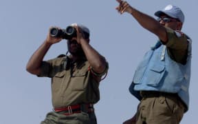 A Fijian UN peacekeeper looks through binoculars at an Israeli post from the Al-Labbouneh hill near Naqoura on the Mediterranean coast 30 July 2000 where fifty Fijian troops took up position.