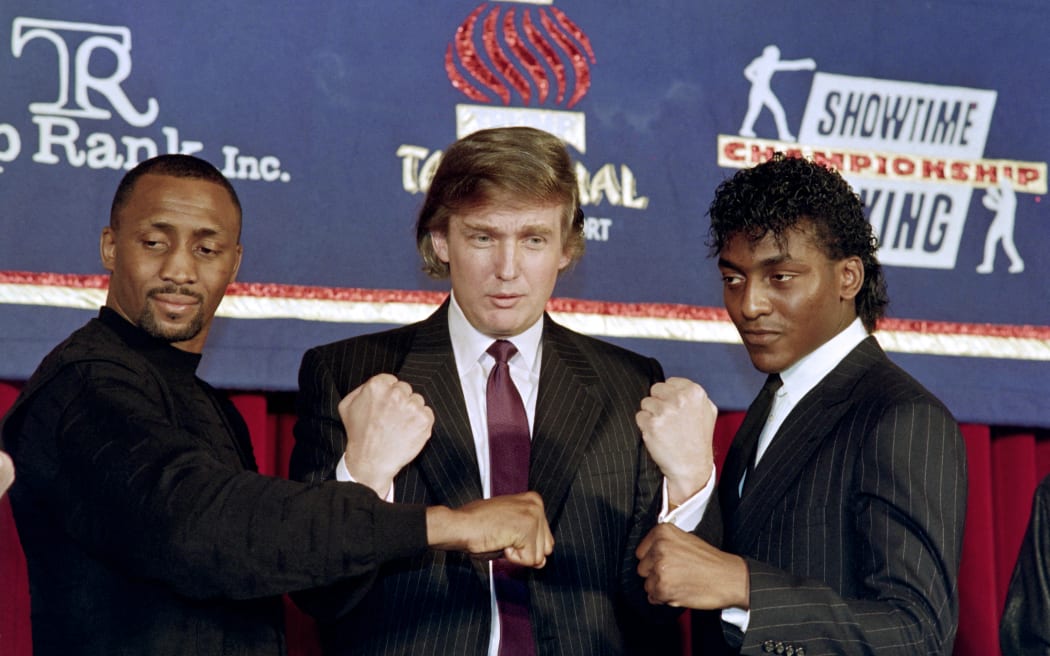 Donald Trump  puts on February 15, 1990 in New York his fists in the iar as Thomas "The Hitman" Hearns (L) and Michael "The Silk" Olajide (R) announce a super middleweight title fight in "The Barrage at Trump Taj" at the new Trump Taj Mahal Casino in Atlantic City on April 28, 1990. Thomas Hearns beat Michael Olajide by UD in round 12 of 12.  AFP PHOTO MARK CARDWELL (Photo by MARK CARDWELL / AFP)