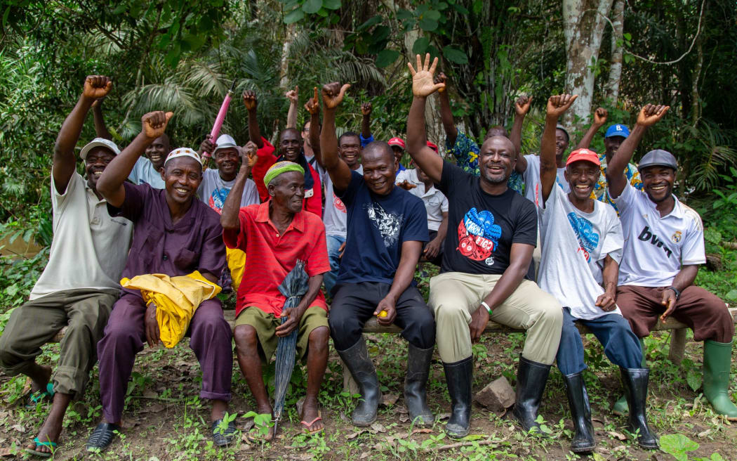 Albert Tucker, Co-Founder of Karma Drinks and Chairman on the Karma Foundation sits with a group of team members. They're all smiling and raising their hands in the air.