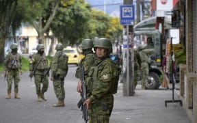 Members of the Army stands guard in a street at the Ciudadela del Ejercito zone in southern Quito, on January 13, 2024, as Ecuador is in a "state of emergency" since the prison escape of one of the country's most powerful narco bosses. Since the escape almost a week ago of the feared leader of the Choneros gang Adolfo Macias, alias "Fito," Ecuador -- which has become a hub for drug trafficking in recent years -- is experiencing an unprecedented security crisis and the gangs, which number some 20,000 members, have gone on a spree of violence, spreading terror in response to the government crackdown on organized crime. (Photo by STRINGER / AFP)