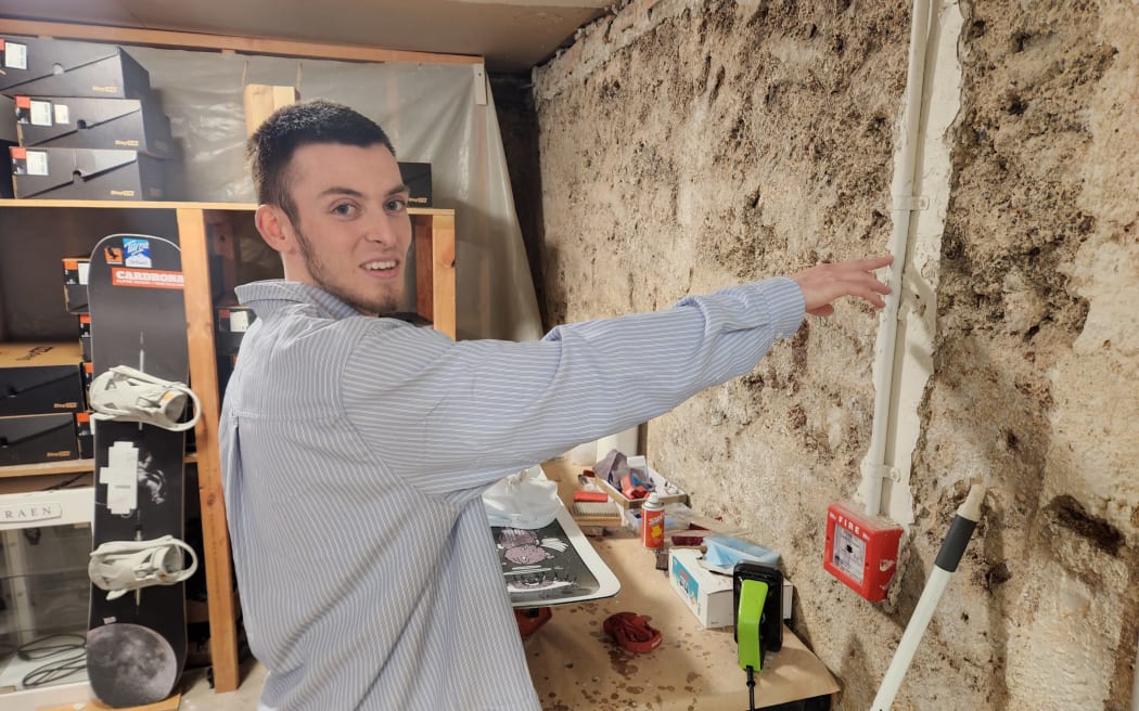 Harry Williams pointing to the height at which the store basement got flooded in the January 2023 floods in Auckland.