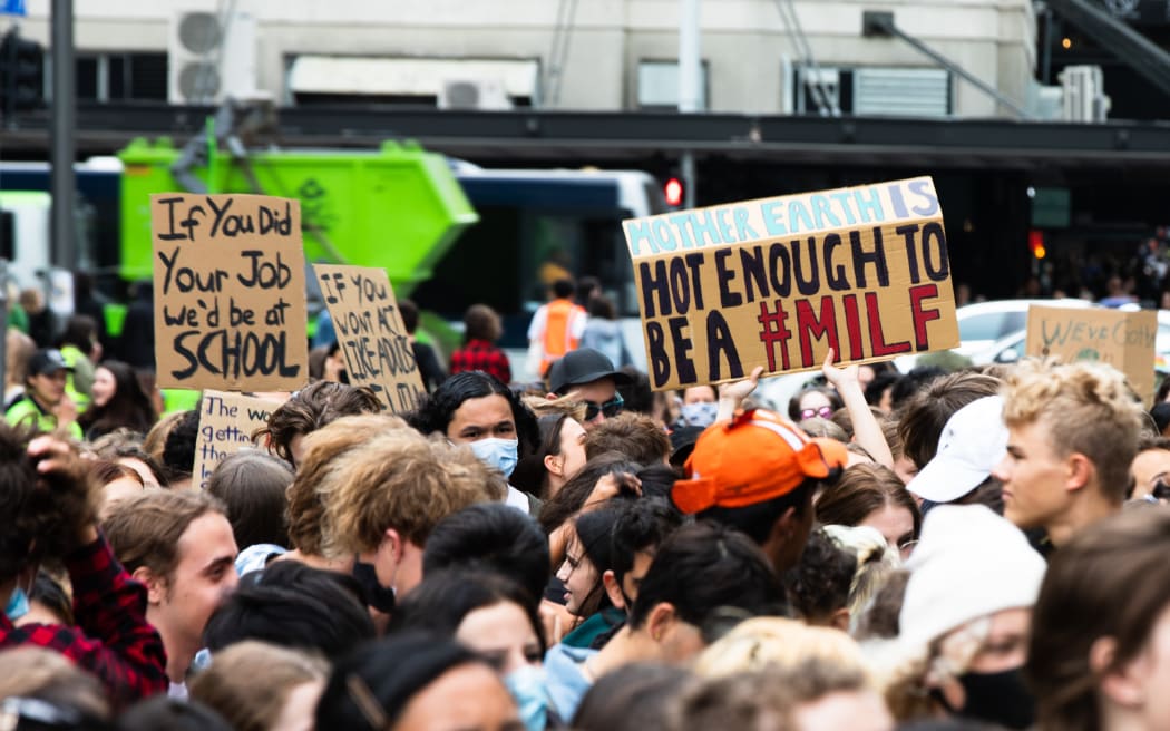 Signs visible as the crowd marches in Auckland.