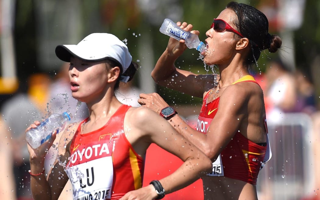 Liu Hong (R) and Lu Xiuzhi of China take on water while competing in the 20km race walk at the 2015 World Championships.