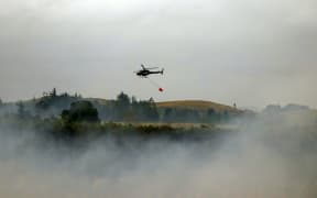 A helicopter with a monsoon bucket at work in Canterbury.