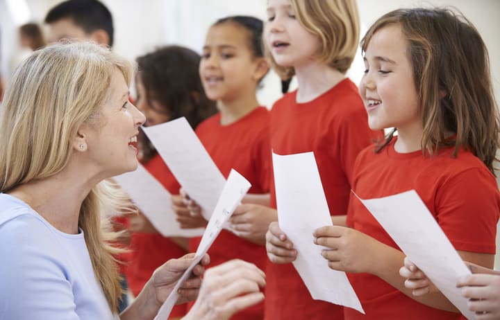 A music teacher helps a group of primary school children singing in a choir (file photo)