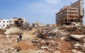 Men walk past debris of buildings caused by flash floods in Derna, eastern Libya, on September 11, 2023.