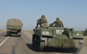 Russian servicemen are seen through a car window as they drive a military vehicle along a road near the border with Ukraine.