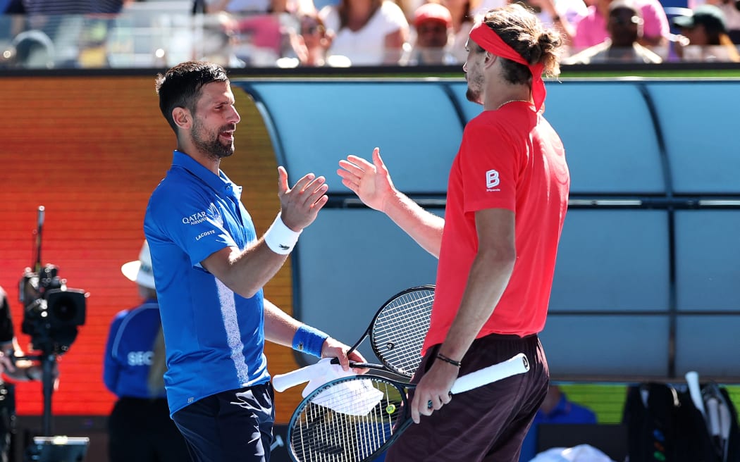 Serbia's Novak Djokovic (L) shakes hands with Germany's Alexander Zverev as he retires during their men's singles semi-final match on day thirteen of the Australian Open tennis tournament in Melbourne on January 24, 2025. (Photo by Martin KEEP / AFP) / -- IMAGE RESTRICTED TO EDITORIAL USE - STRICTLY NO COMMERCIAL USE --