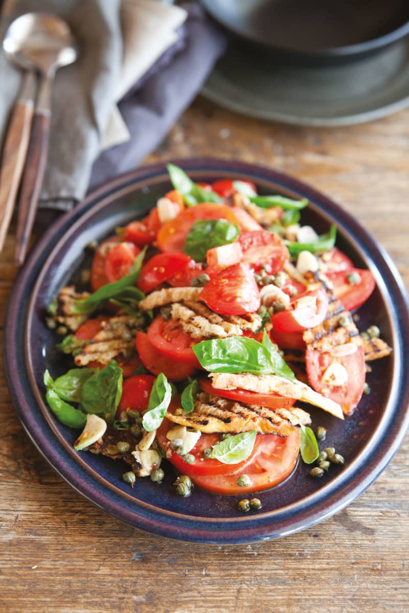 Fresh bite-sized tomato chunks sit on a bed of basil leaves