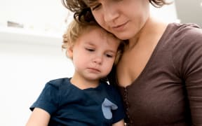 Close up portrait of a cute little boy crying on mothers lap after being scared