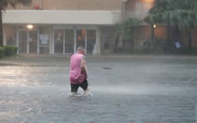 A man walks though a flooded parking lot as the outer bands of Hurricane Sally come ashore in Gulf Shores, Alambama, on 15 September 2020.