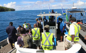 Solomon Islands government officials (Wearing high visibility vests) handing over the two fishermen to their Bougainville counterparts.