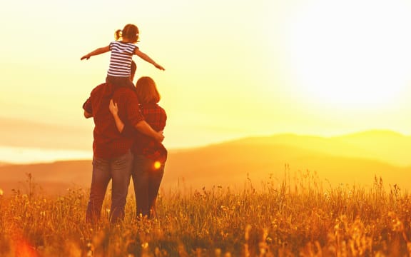 Happy family: mother father and child daughter on nature  on sunset