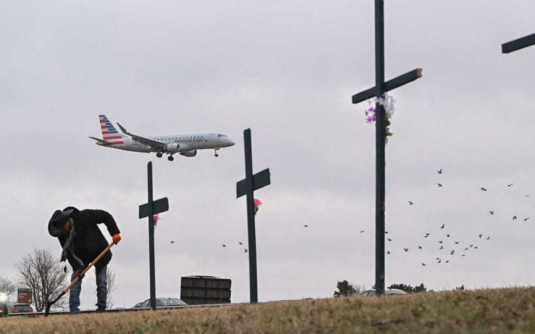 Roberto Marquez from Dallas, Texas, sets up a makeshift memorial on 31 January for the victims of the deadly midair collision near Reagan National Airport in Arlington, Virginia.