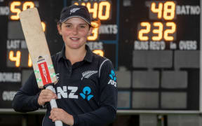 Amelia Kerr in front the scoreboard showing her record score.