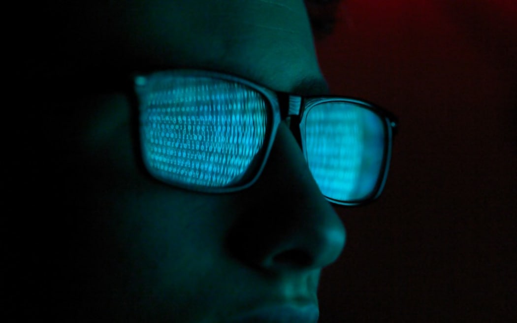 Cybercriminalité, reflet dans des lunettes d'un virus piratant un ordinateur, gros plan du visage (Photo d'Andrew Brookes / Cultura Creative / Cultura Creative via AFP)
