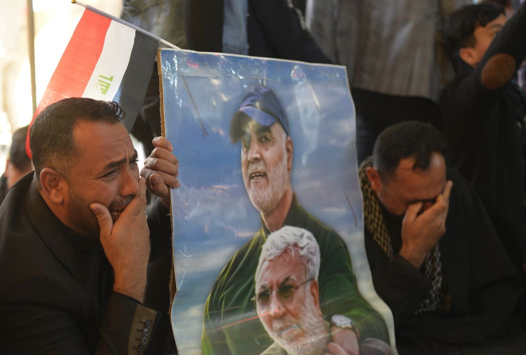 Iraqis holding portraits of slain commander Abu Mahdi al-Muhandis (bottom) and Iranian Revolutionary Guards commander Qasem Soleimani, during a ceremony on January 3, marking the first anniversary of their killing in a US drone strike.