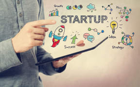 Young man pointing at Startup concept over a tablet computer.