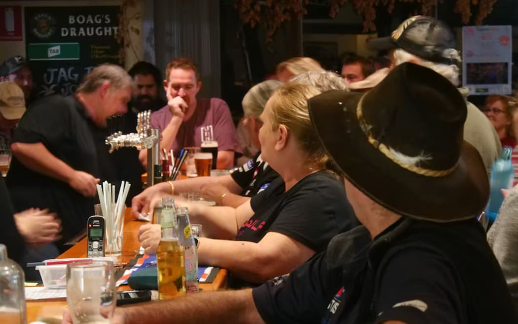 Australian pub with people socialising and drinking at counter.