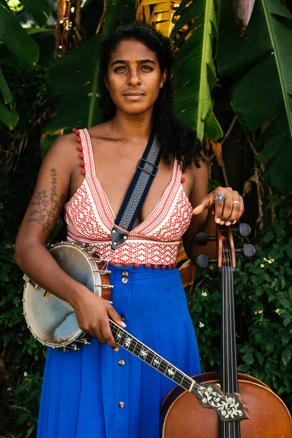 American musician Leyla McCalla stands with banjo and cello