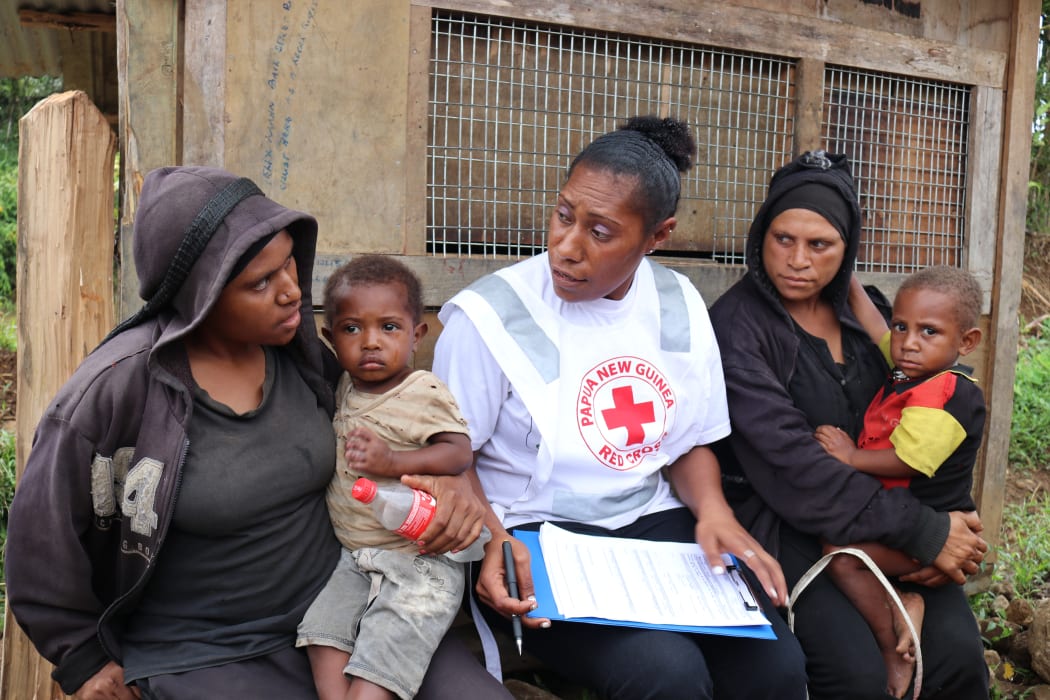 A Red Cross volunteer talks with two widows whose husbands were both killed in a landslide following the earthquake.