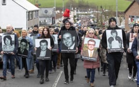 Family members carry photographs of those killed on Bloody Sunday at a memorial march to the Bogside for a wreath laying ceremony at a monument to those killed on the day, in Londonderry (Derry), Northern Ireland, on January 30, 2022, on the 50th anniversary of the Bloody Sunday shootings. The Northern Irish city of Londonderry began commemorations Sunday of one of the darkest days in modern UK history when, 50 years ago, British troops without provocation killed 13 unarmed civil rights protesters. (Photo by PAUL FAITH / AFP)