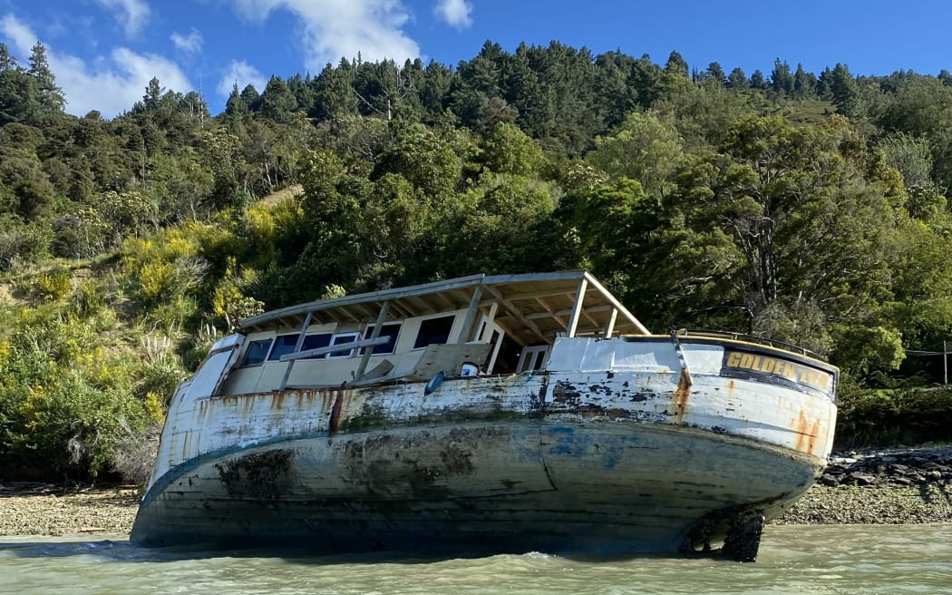 Old and damaged wooden fishing boat aground in Marlborough Sound