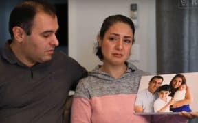 Mohy Sharifi with her husband Siamak Mosaferi holding a family photo taken before the crash killed their two children.