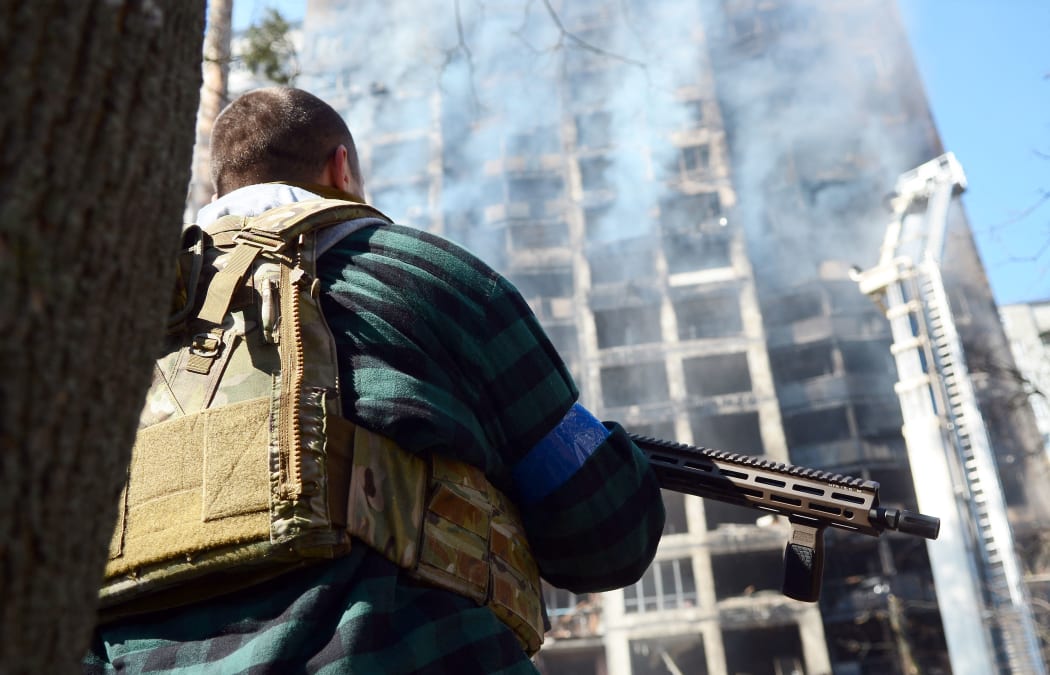 An armed man in a bulletproof vest is seen at the site of shelling of a residential building by the Russian troops in Svyatoshyn district of Kyiv, capital of Ukraine, on March 15, 2022.