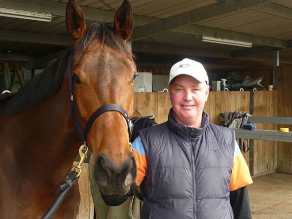 Horse trainer Tony Pike holding horse by reins
