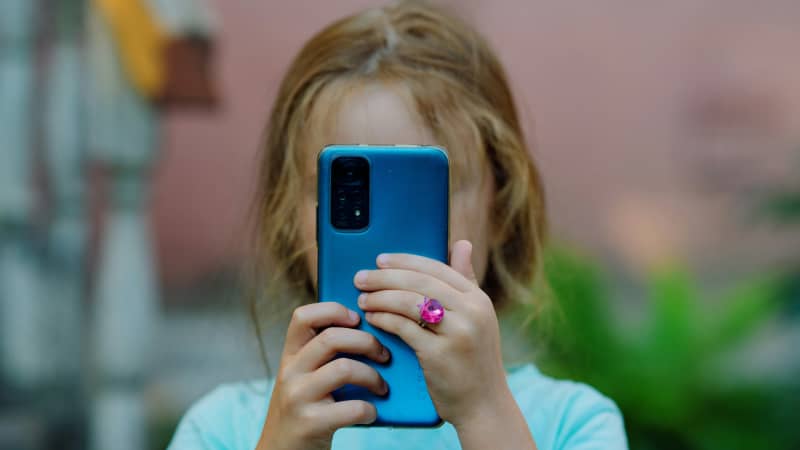 Girl holds up phone to her face.