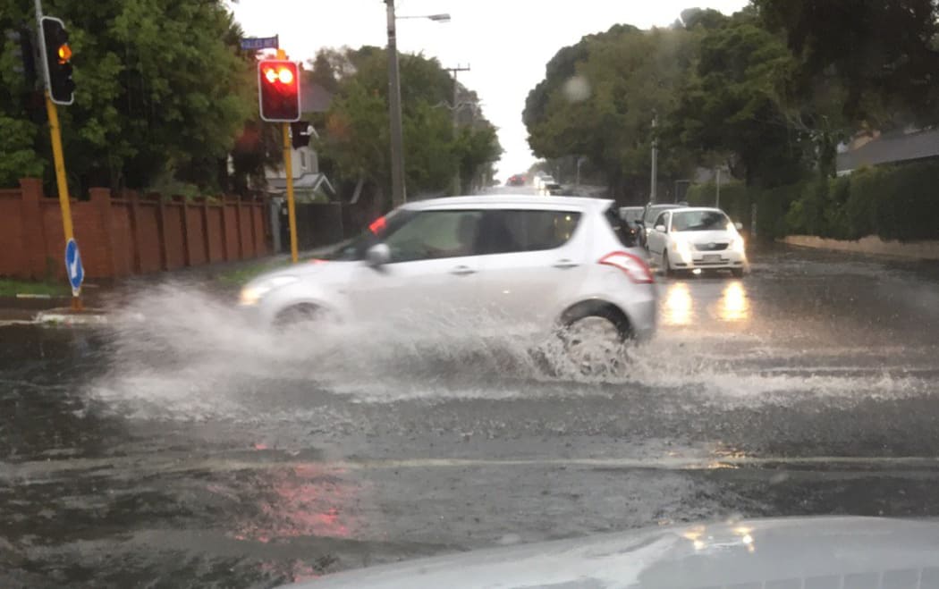A car drives through surface flooding on Gillies Ave, Auckland.