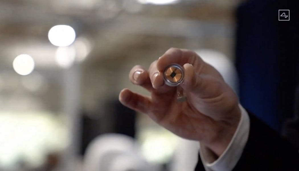 A Neuralink disk implant held by Elon Musk.