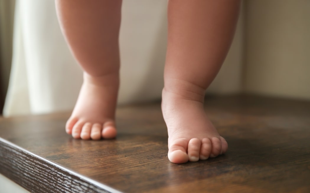 Baby's legs walking on wooden surface