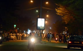 People gather on Kwame Nkruma avenue near Hotel Splendid as gunfire continues.