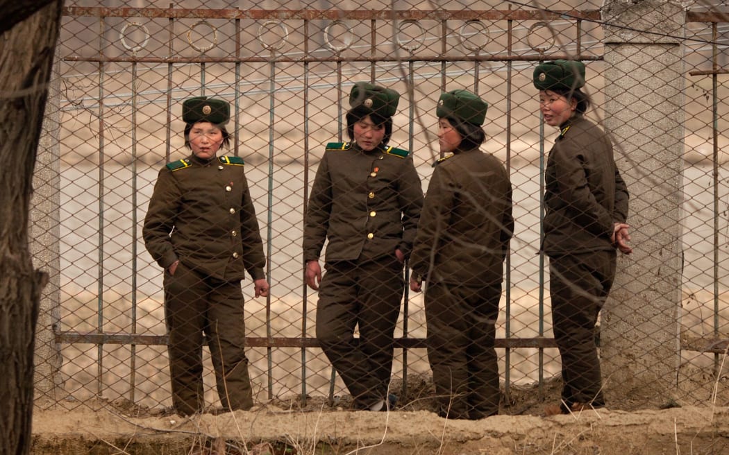 Female North Korean soldiers stand at a fence near Pyongyang.