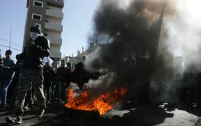 Palestinian protesters walk by a fire during a protest in the southern Gaza Strip town of Rafah.