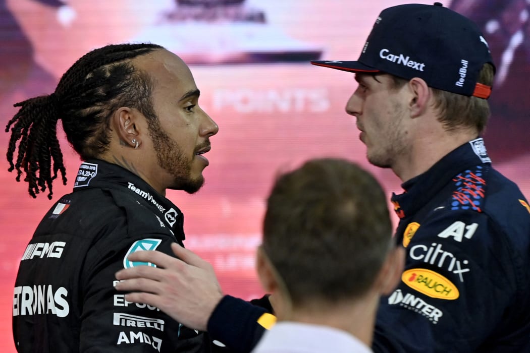Champion Red Bull's Dutch driver Max Verstappen (right) greets second-placed Mercedes' British driver Lewis Hamilton after the Abu Dhabi F1 Grand Prix at the Yas Marina Circuit on 12 December, 2021.