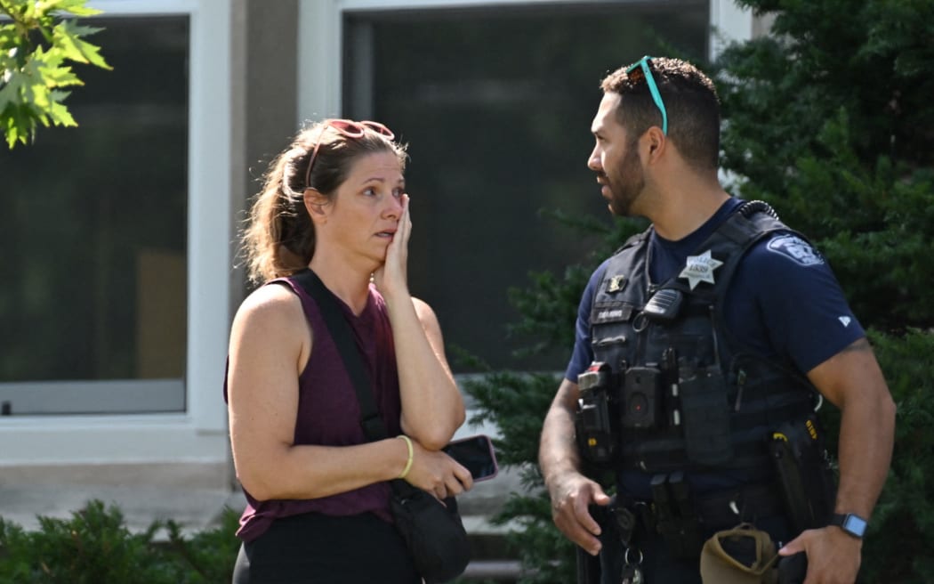 A woman speaks to a police officer near the scene of a shooting near Annunciation Catholic School in Minneapolis, Minneosta, on August 27, 2025.