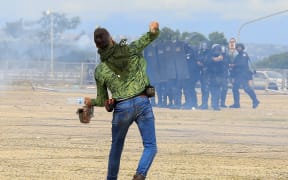 A supporter of Brazilian former President Jair Bolsonaro throws stones at security forces during clashes outside Planalto Presidential Palace in Brasilia on January 8, 2023. - Hundreds of supporters of Brazil's far-right ex-president Jair Bolsonaro broke through police barricades and stormed into Congress, the presidential palace and the Supreme Court Sunday, in a dramatic protest against President Luiz Inacio Lula da Silva's inauguration last week. (Photo by Sergio Lima / AFP)