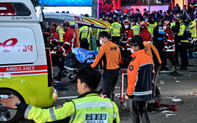 Paramedics attend to a victim believed to have suffered from cardiac arrest, in the popular nightlife district of Itaewon in Seoul on October 30, 2022. - Dozens of people suffered from cardiac arrest in the South Korean capital Seoul after thousands of people crowded into narrow streets in the city's Itaewon neighbourhood to celebrate Halloween, local officials said. (Photo by JUNG YEON-JE / AFP)